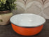 Vintage emaille schaal met oranje buitenkant en witte binnenkant, 18,5 cm doorsnee en 7 cm hoog.
