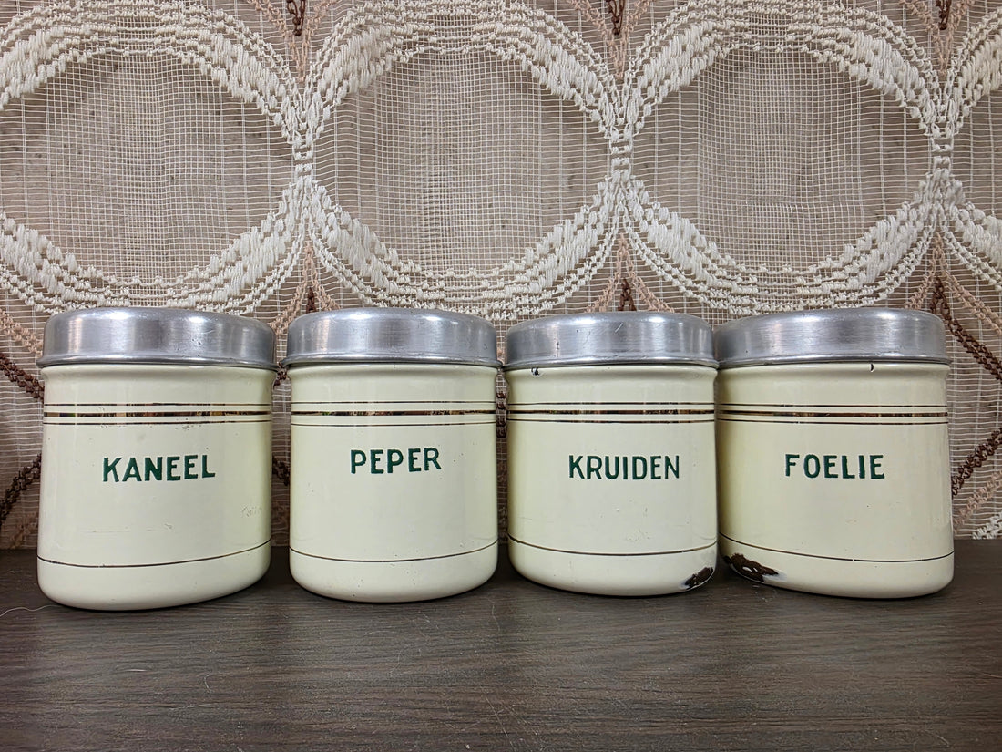 Vier vintage emaille kruidenbussen met aluminium deksels en de opschriften Kaneel, Peper, Kruiden en Foelie.
