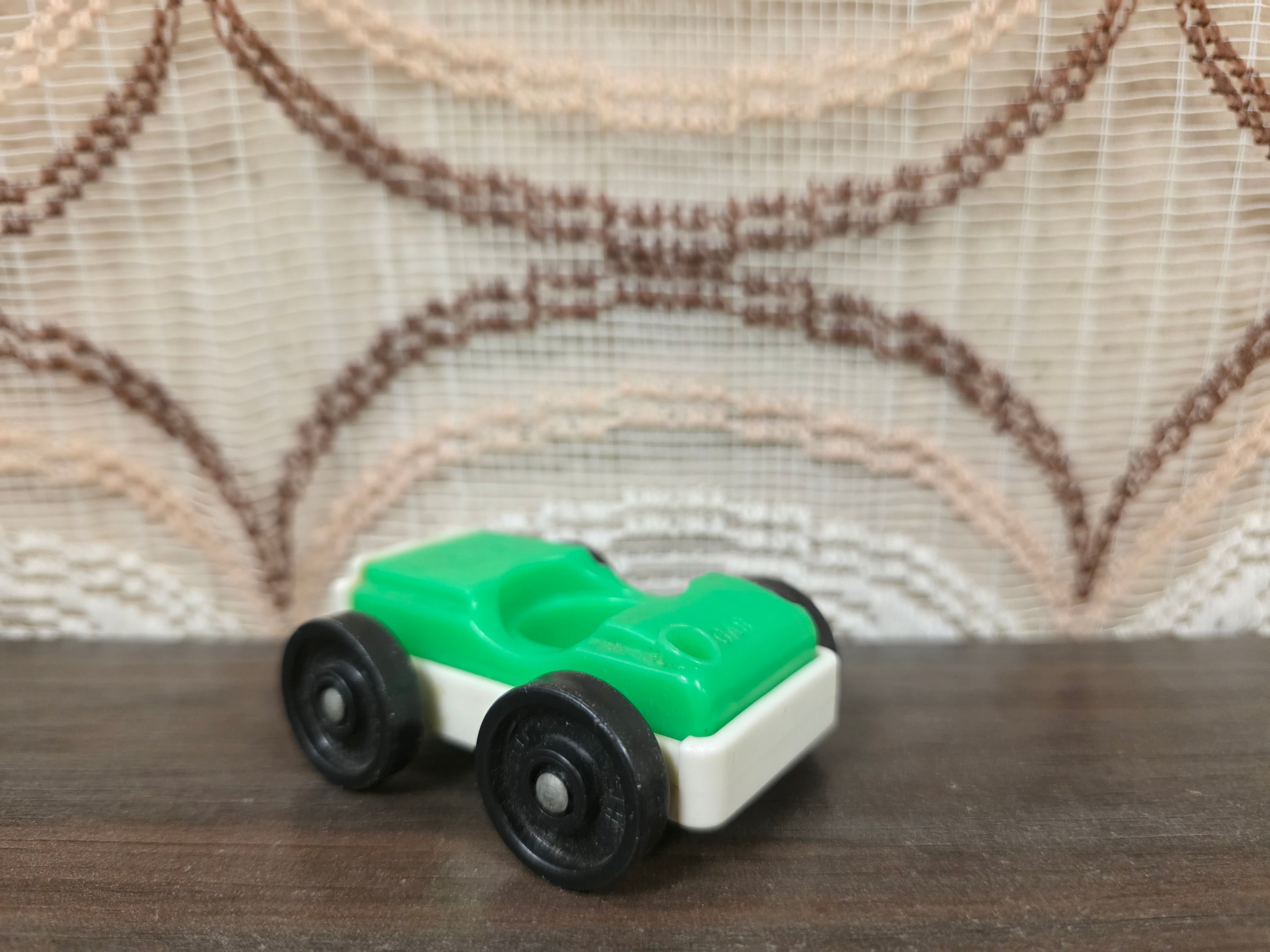 Vintage Fisher-Price autootje in groen wit met zwarte wielen.