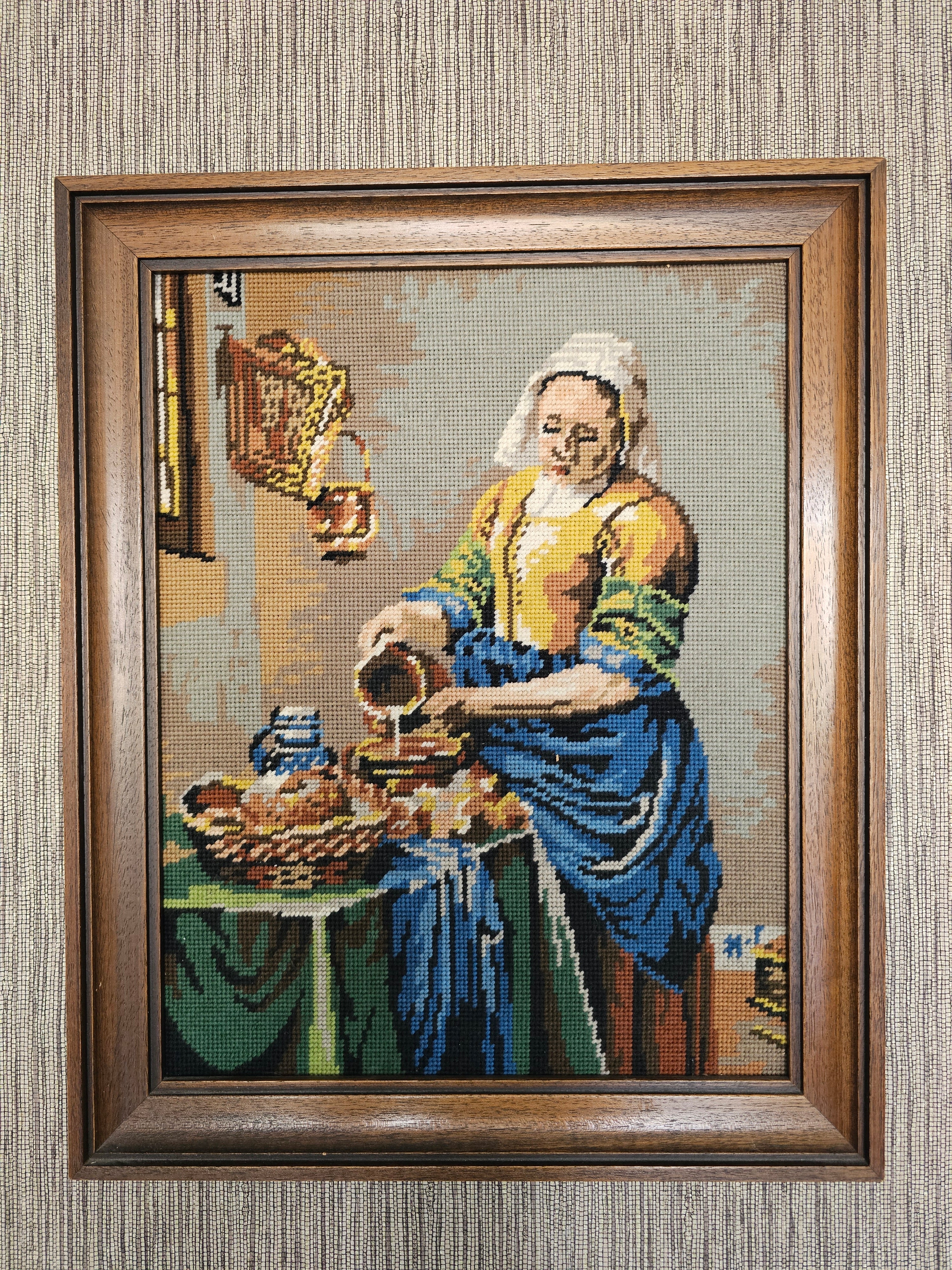 Geborduurd schilderij van Het melkmeisje van Vermeer, ingelijst in hout, afmeting 52 x 42,5 x 4,5 cm.