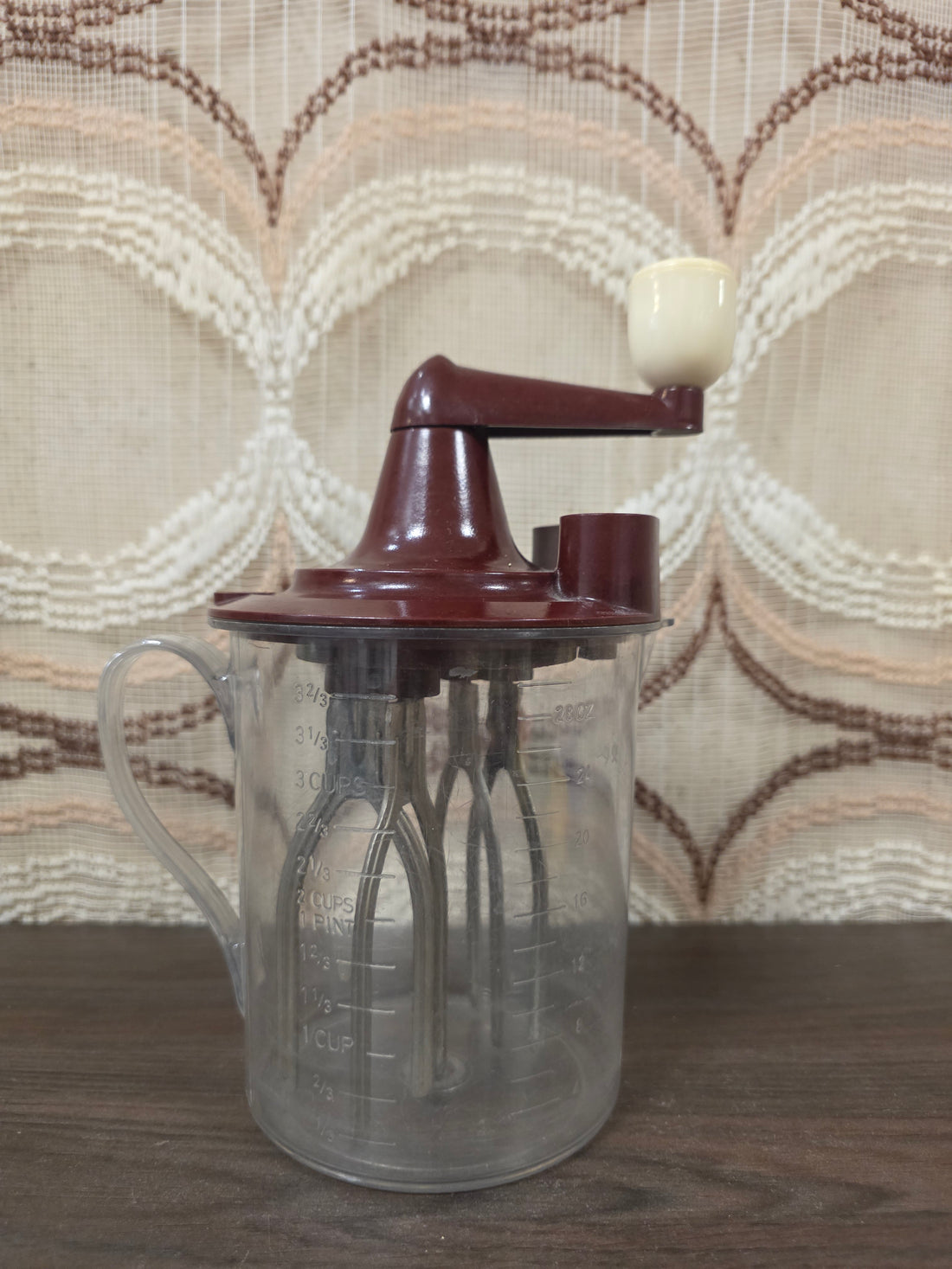 Vintage Maineck handmixer uit de jaren 50 met transparante mengkan en bordeauxrode handzwengel.