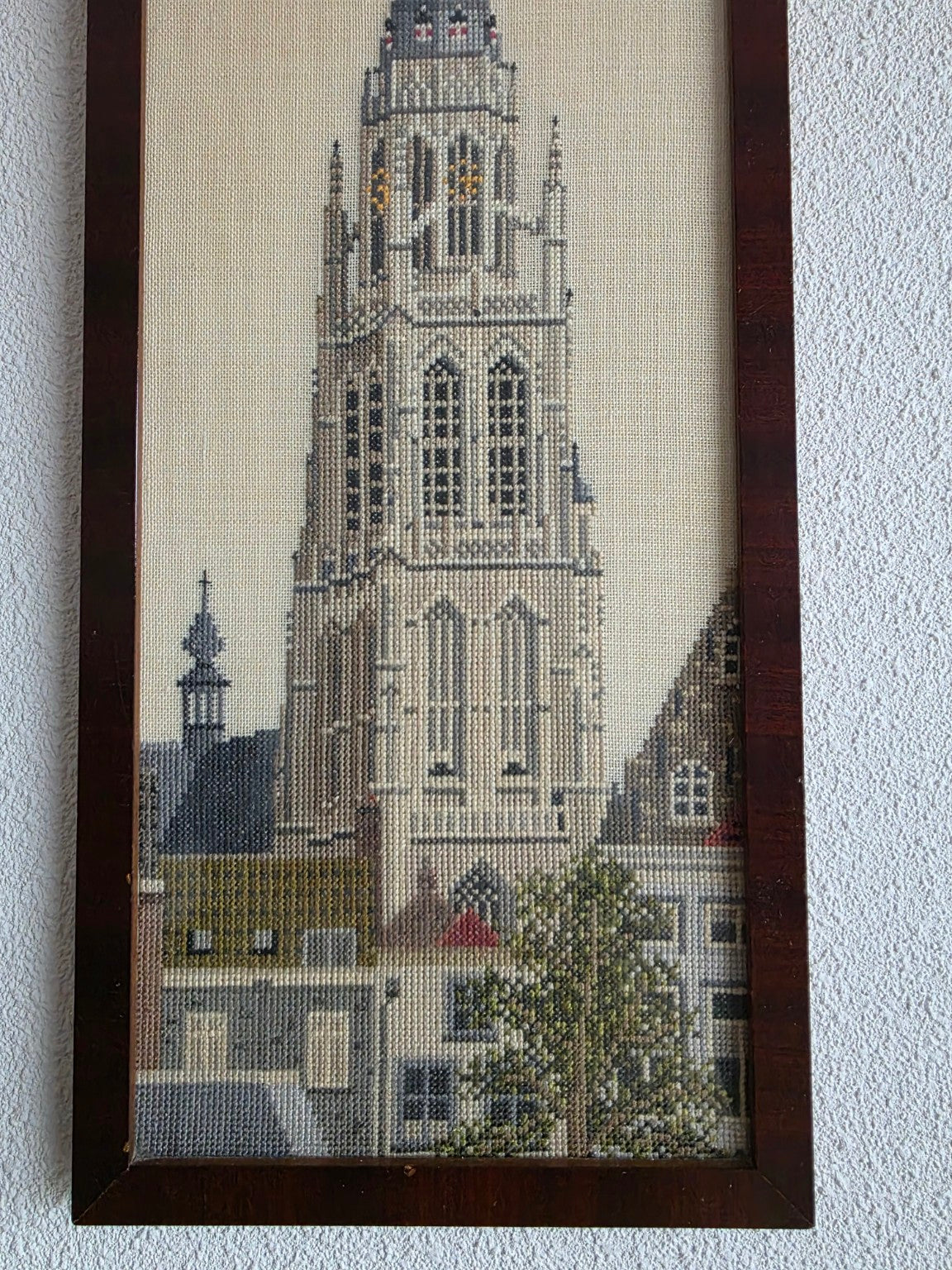 Detail van het borduurwerk met de toren, huizen en boom
