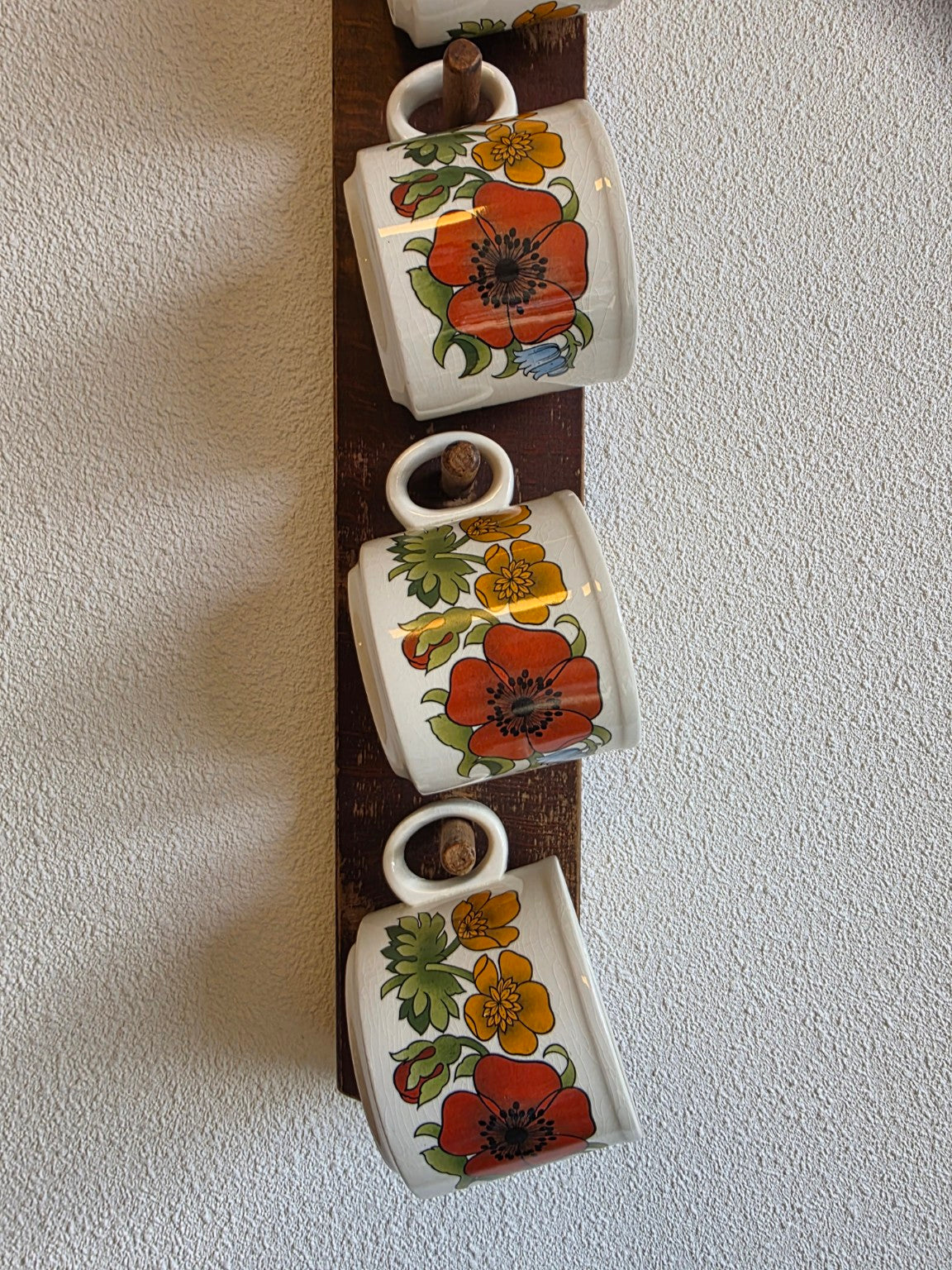 Onderste kopjes met bloemen op het houten mokkenrek