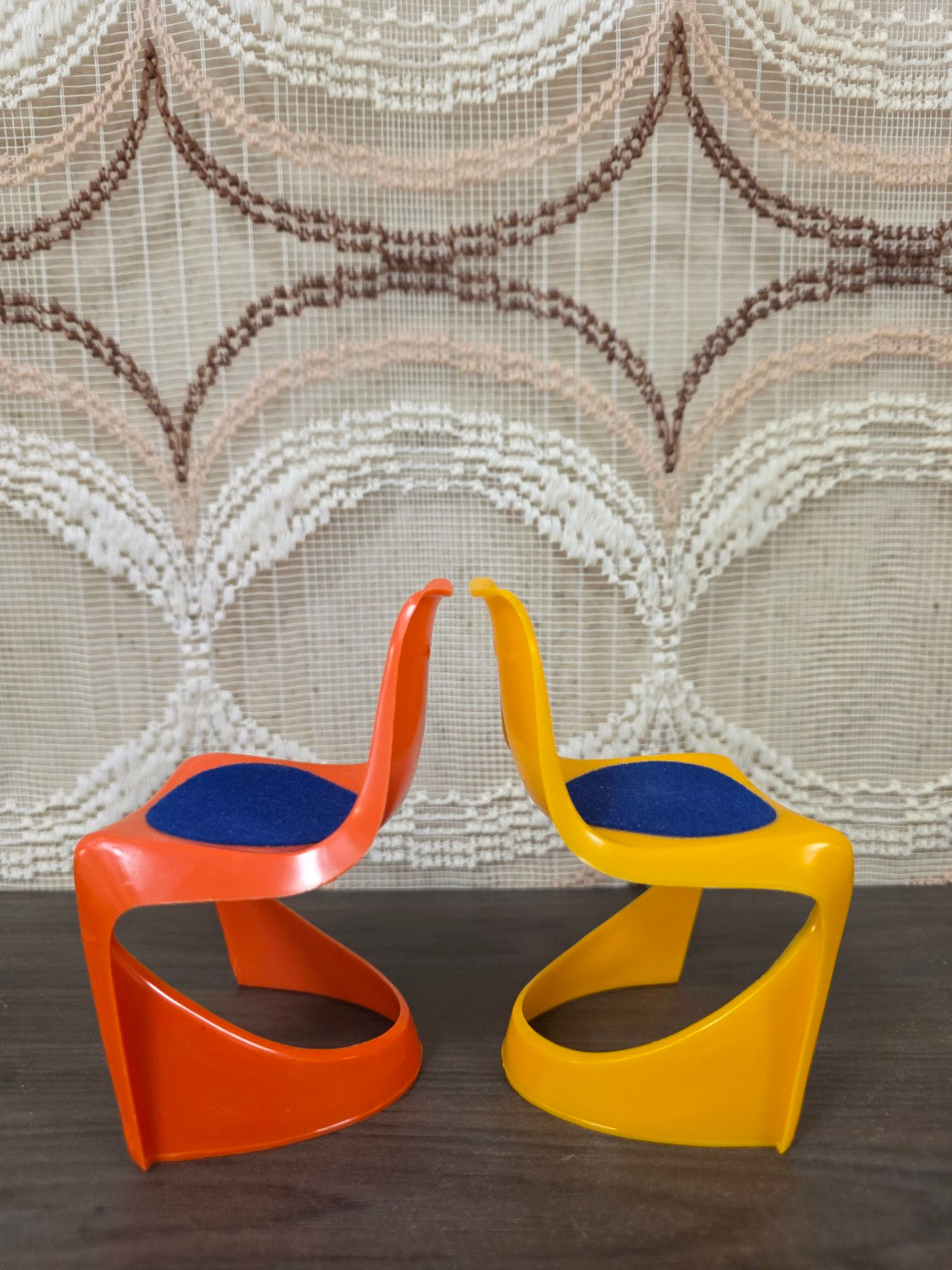 Zijaanzicht van oranje en gele Helly poppenstoelen met gebogen kunststof onderstel