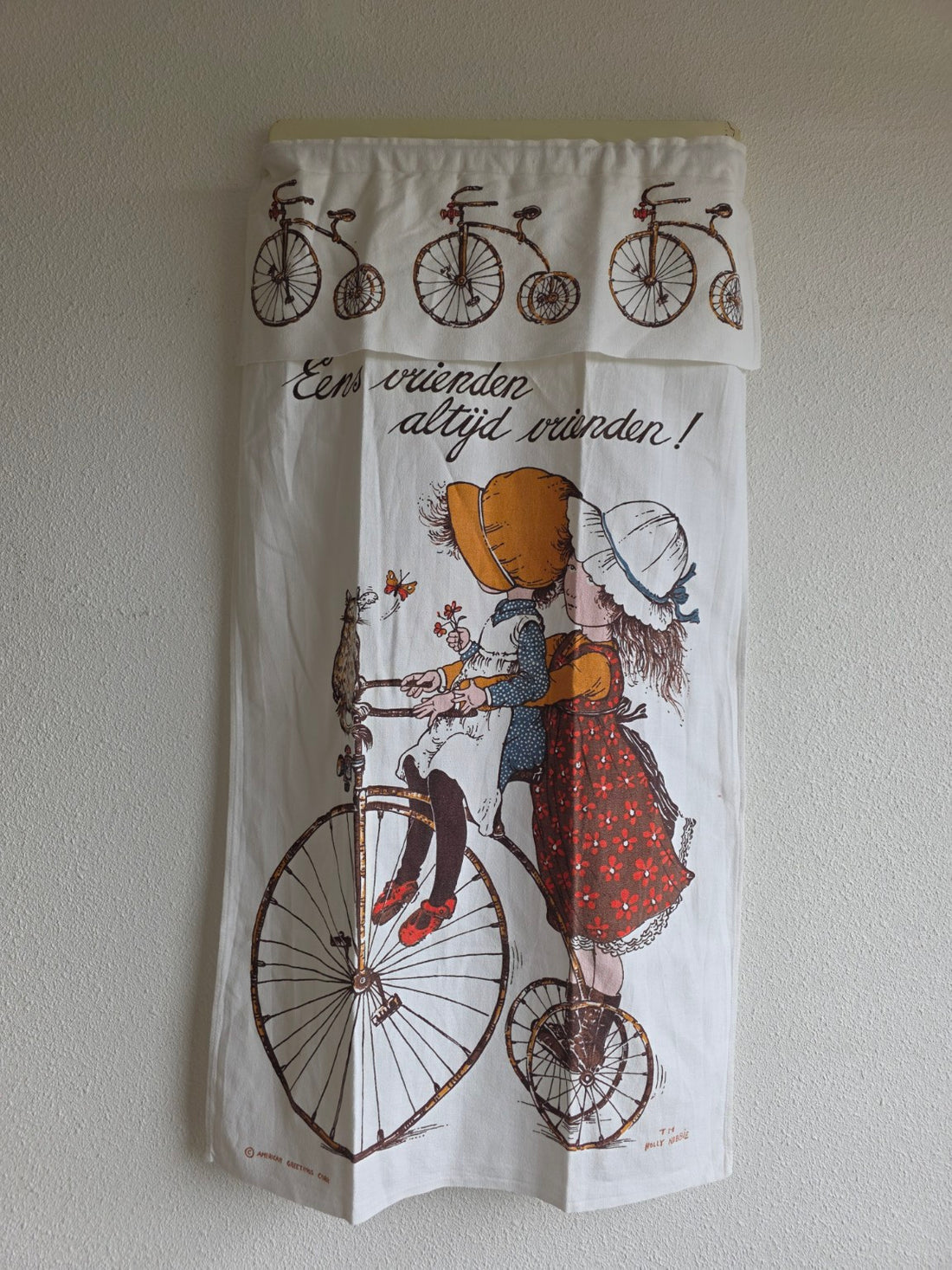 Vintage Holly Hobbie afdekdoek met twee meisjes op een fiets en de tekst Eens vrienden, altijd vrienden