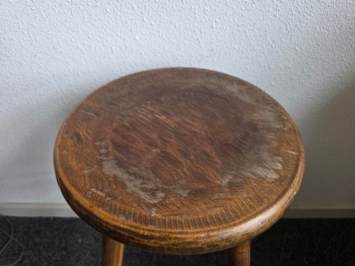 Ronde houten zitting met krassen, lichte plekken en slijtage