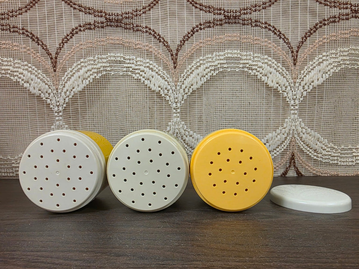 Drie Tupperware strooideksels met gaatjes en een losse witte afsluitdeksel