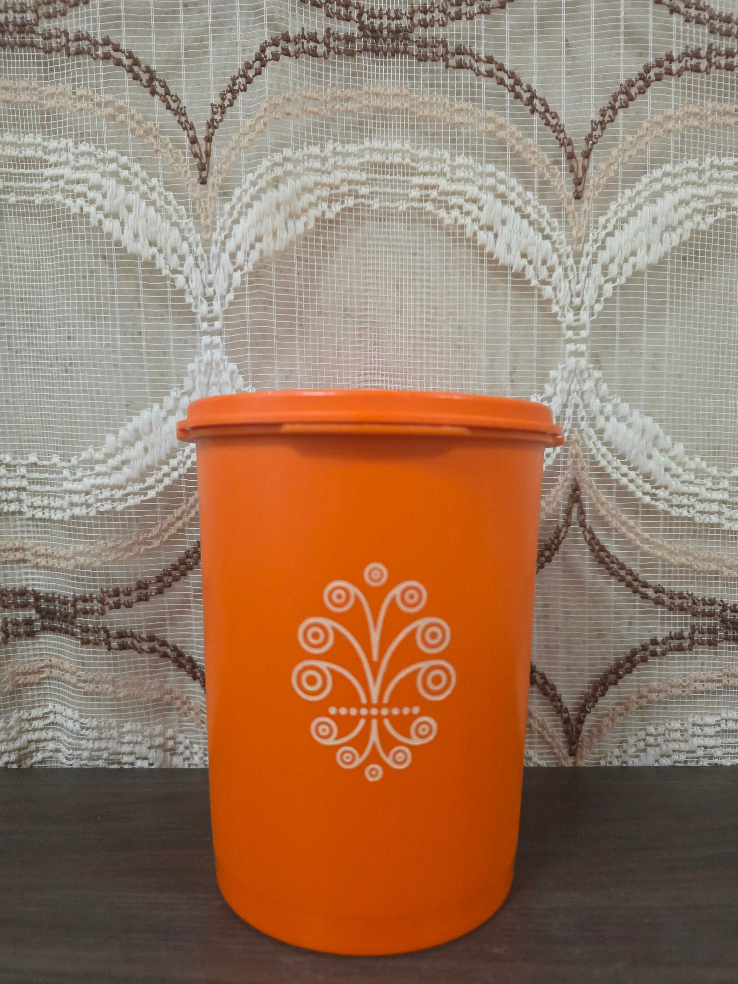 Vintage oranje Tupperware voorraadbus met wit decor en originele sterdeksel. 15.5 cm hoog