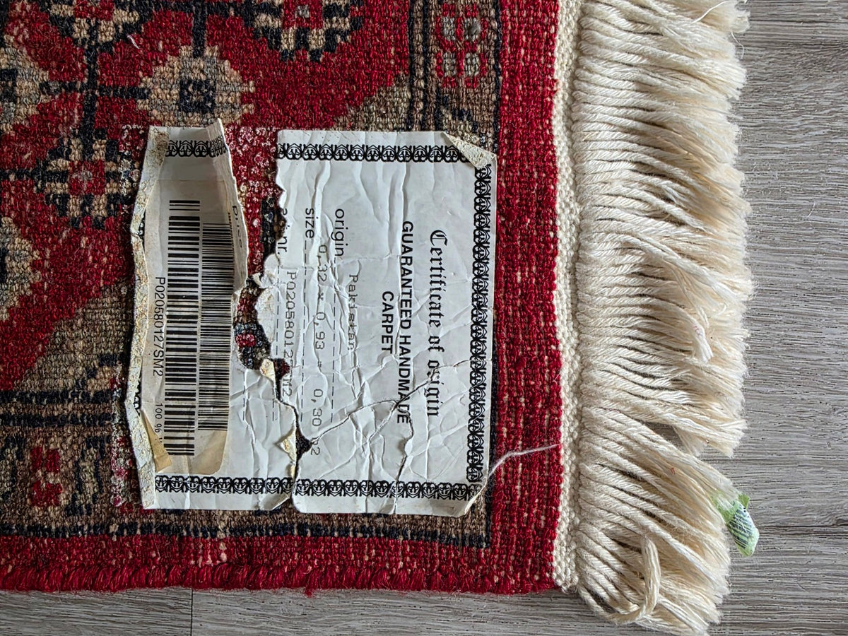 Achterzijde tafelloper met herkomstetiket Pakistan en maat 32 bij 93 cm