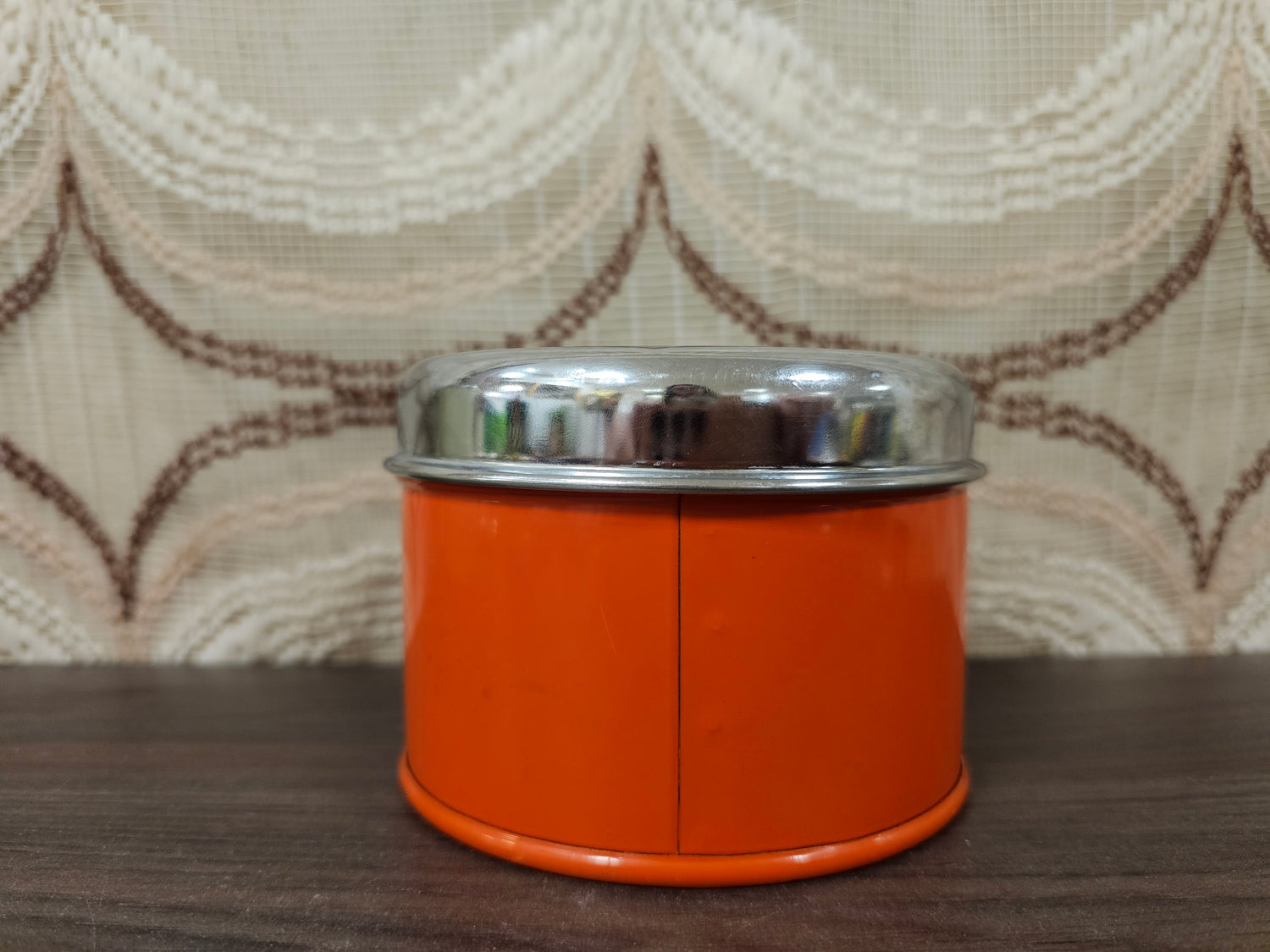 Theeblik oranje met zwarte opdruk en zilverkleurig deksel