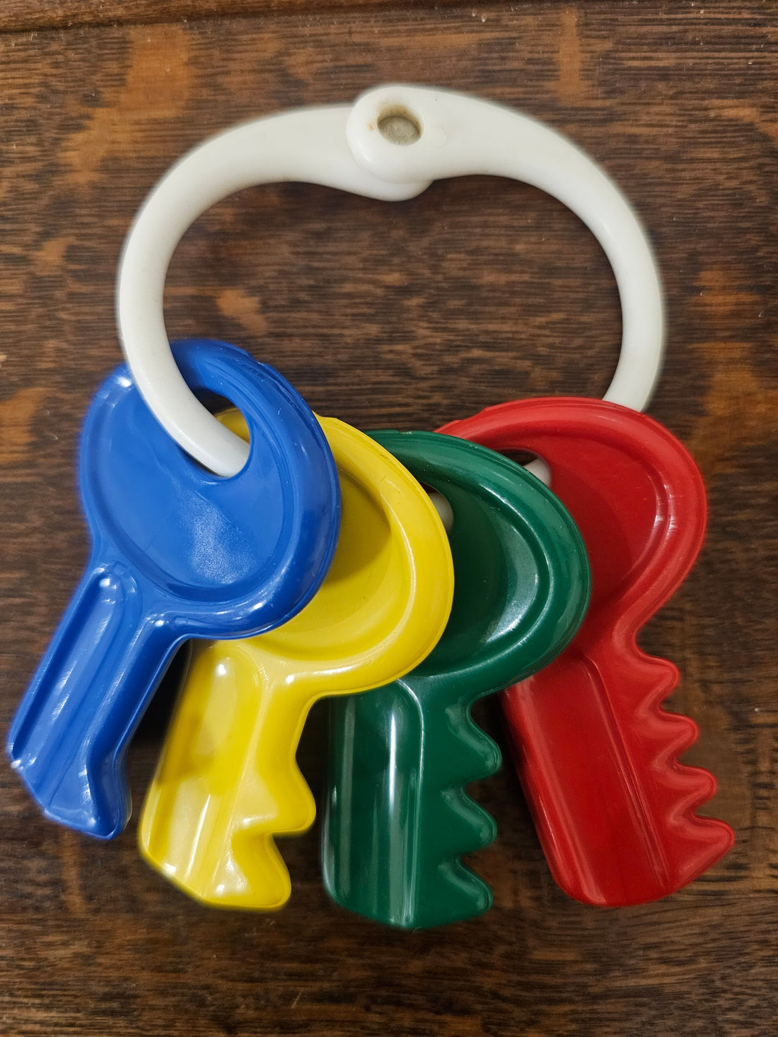 Kleurrijke vintage Ambi Toys sleutels uit de jaren ’70/’80 aan een witte ring, in rood, geel, blauw en groen.