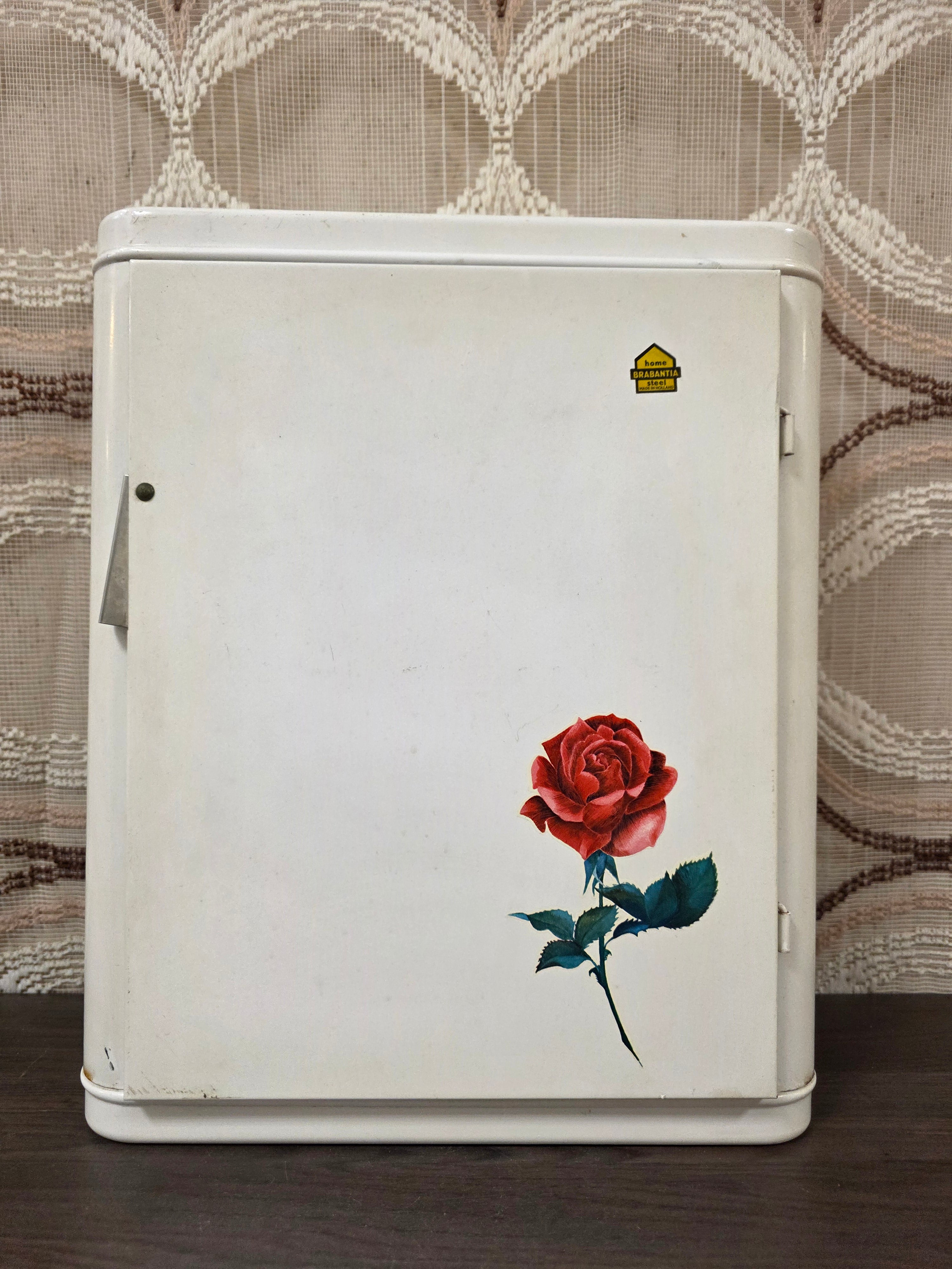 Vintage wit metalen Brabantia medicijnkastje met rode roos op de deur en plankje binnenin