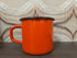 Vintage oranje emaille mok met zwarte rand, 8,5 cm hoog en 10,5 cm diameter.