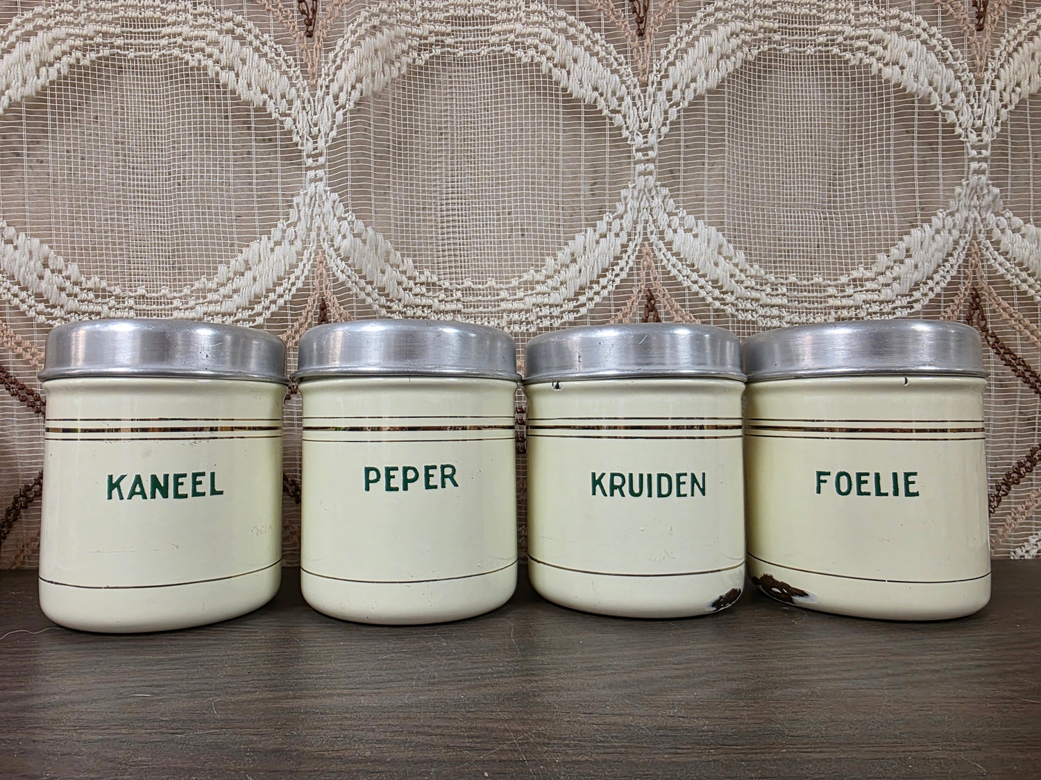 Vier vintage emaille kruidenbussen met aluminium deksels en de opschriften Kaneel, Peper, Kruiden en Foelie.