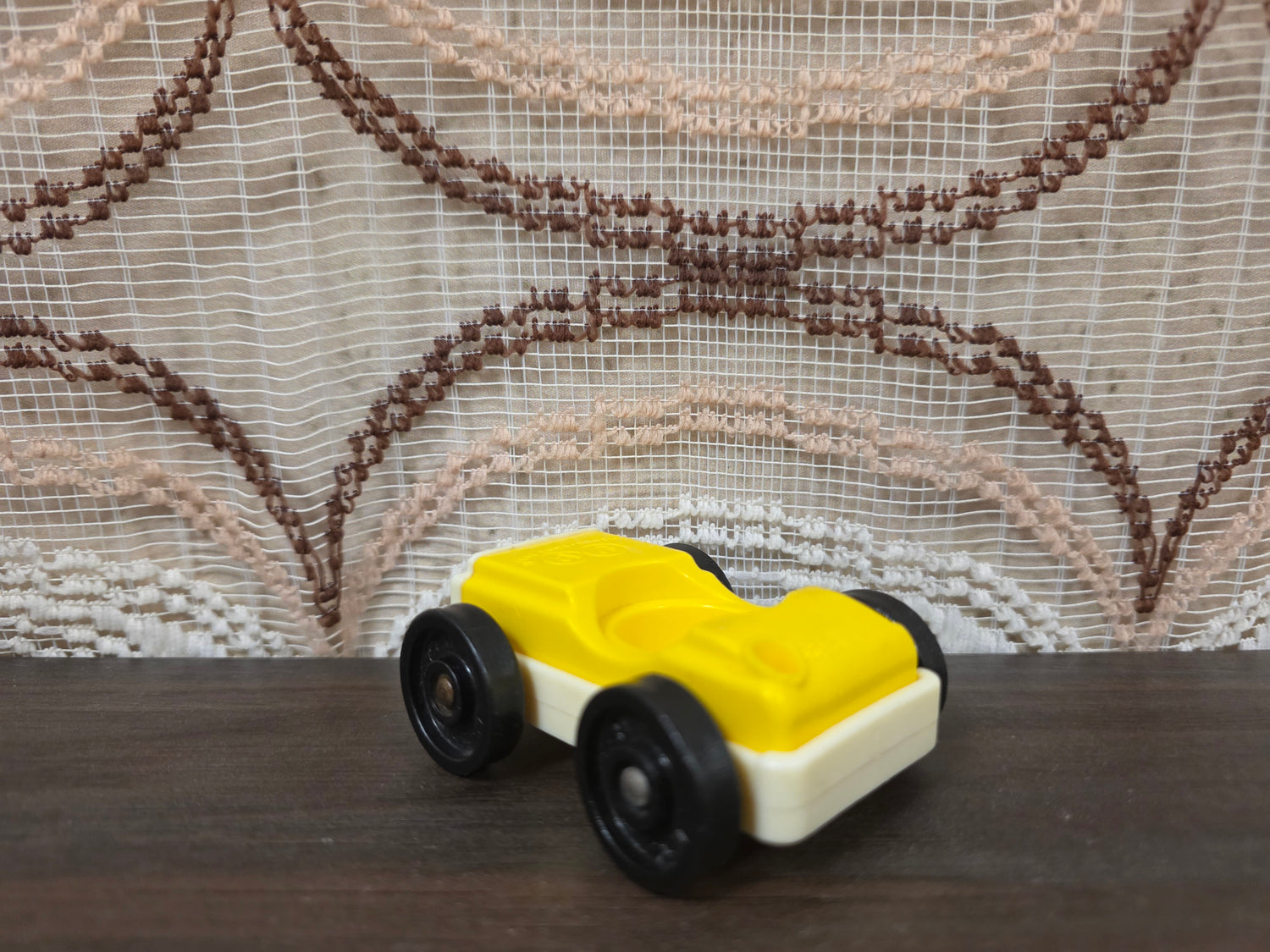 Vintage Fisher-Price autootje in geel wit met zwarte wielen.