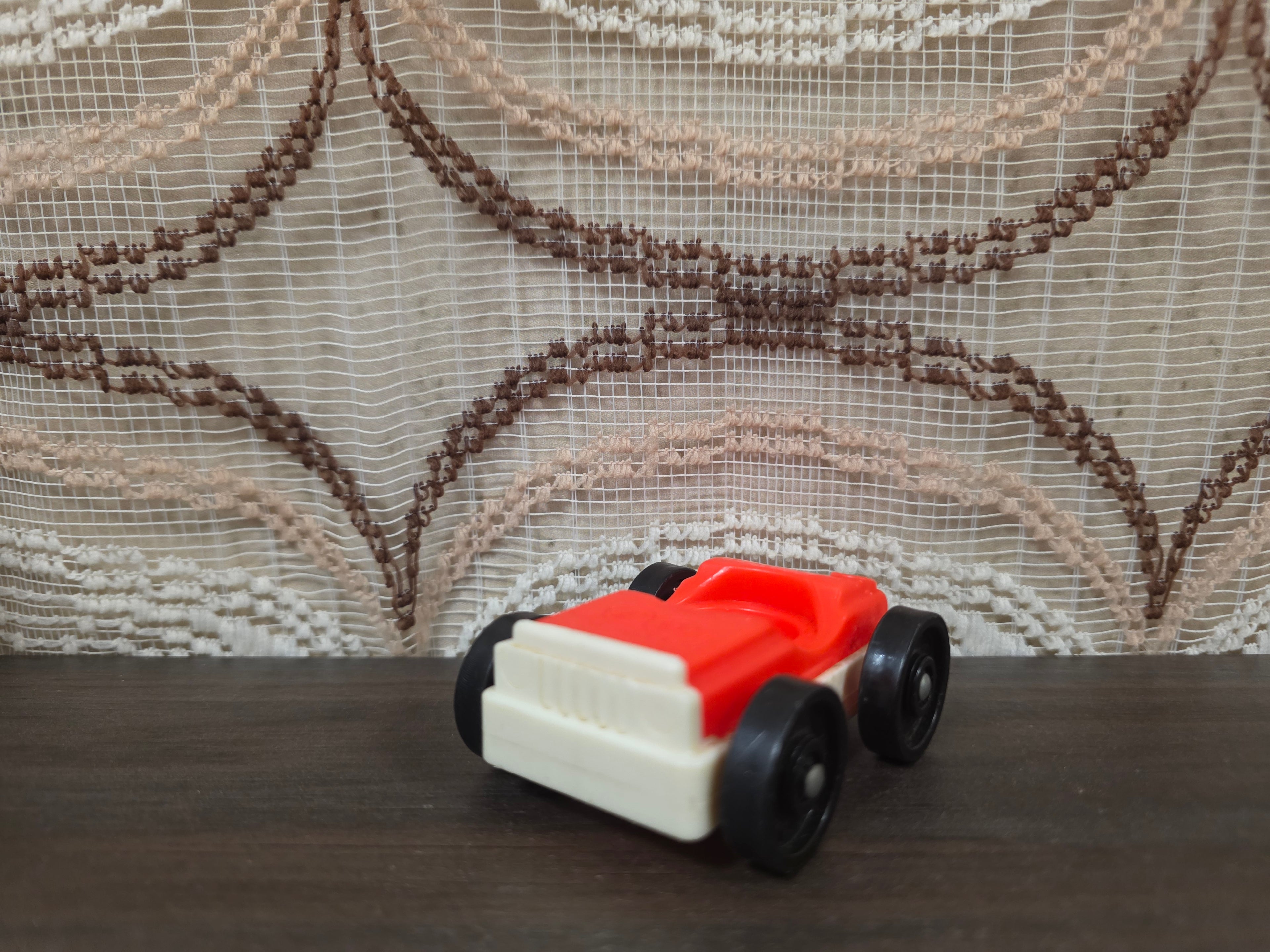 Vintage Fisher-Price autootje in rood wit met zwarte wielen.