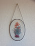 Vintage glas-in-lood raamhanger met bloemen in ovaal metalen frame en ophangketting.
