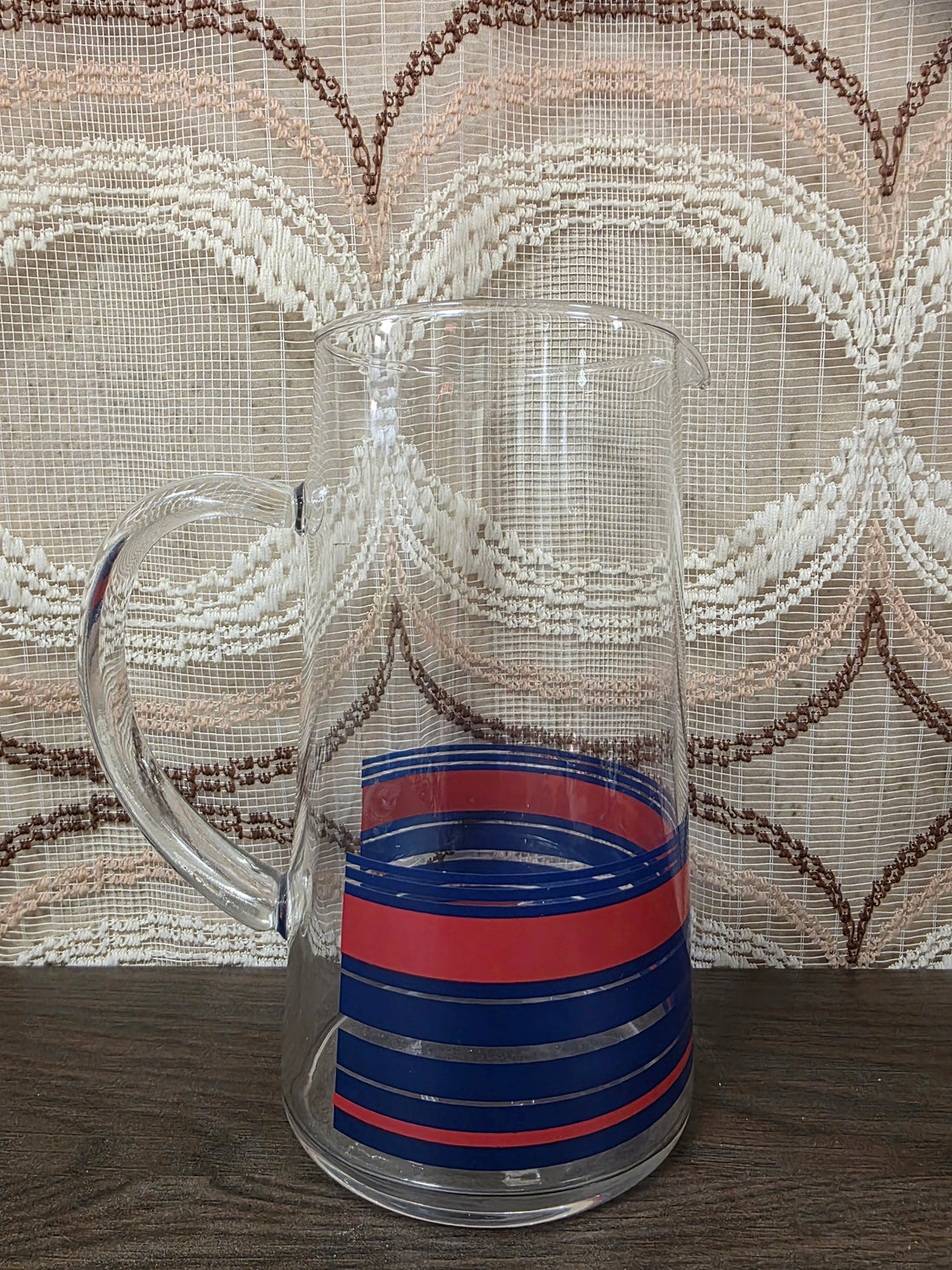 Vintage glazen karaf met rode en blauwe strepen en een glazen handvat.