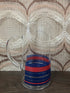 Vintage glazen karaf met rode en blauwe strepen en een glazen handvat.