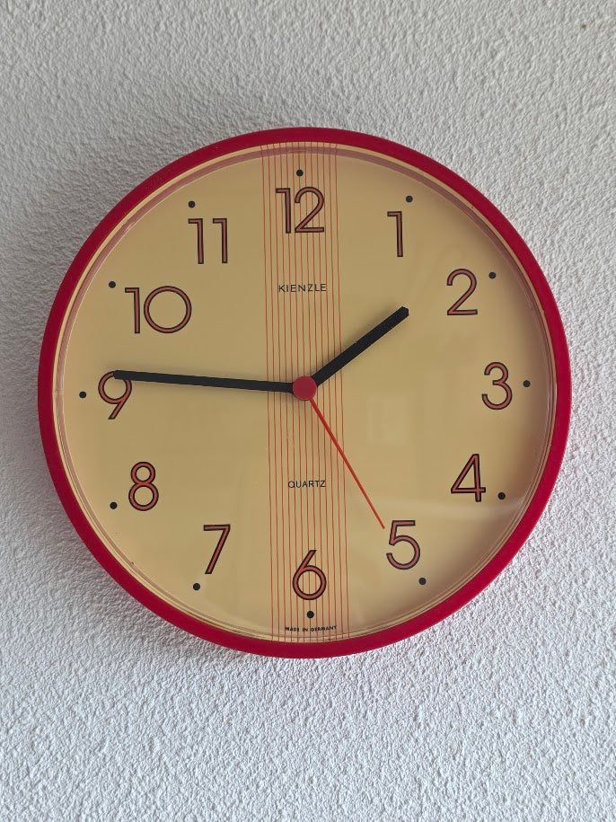 Vintage Kienzle quartz wandklok met rode rand en crèmekleurige wijzerplaat, diameter 22 cm.