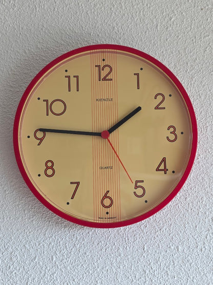 Vintage Kienzle quartz wandklok met rode rand en crèmekleurige wijzerplaat, diameter 22 cm.
