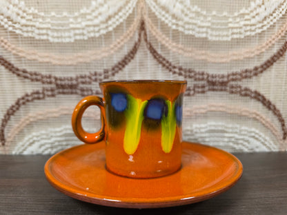 Kop en schotel met paars en geel fat lava glazuur op oranje ondergrond