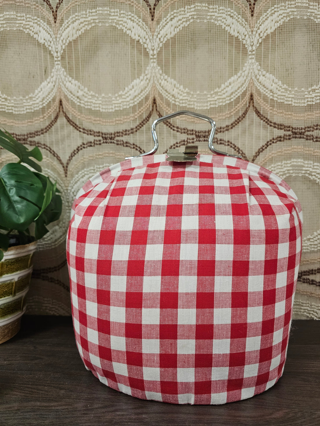 Theebeurs met knip van rood-wit geblokte stof om theepot warm te houden