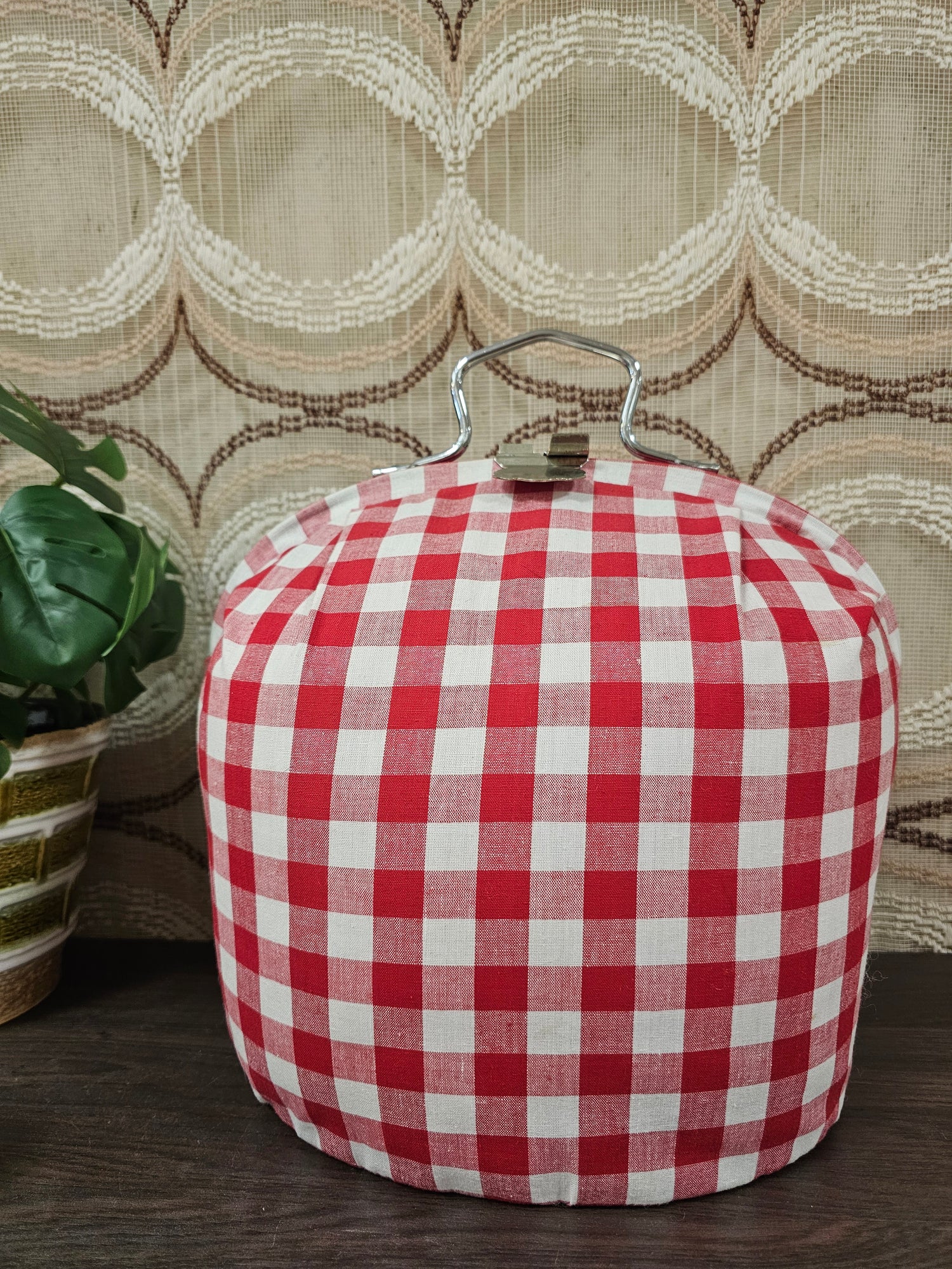 Theebeurs met knip van rood-wit geblokte stof om theepot warm te houden