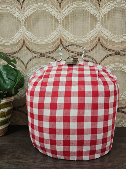 Theebeurs met knip van rood-wit geblokte stof om theepot warm te houden