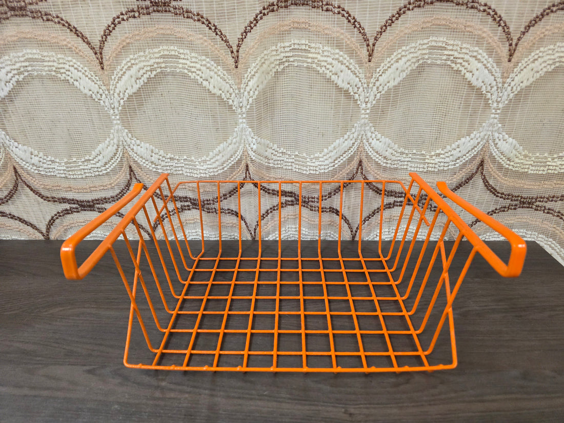 Vintage oranje Tomado draadmand voor montage onder een plank.