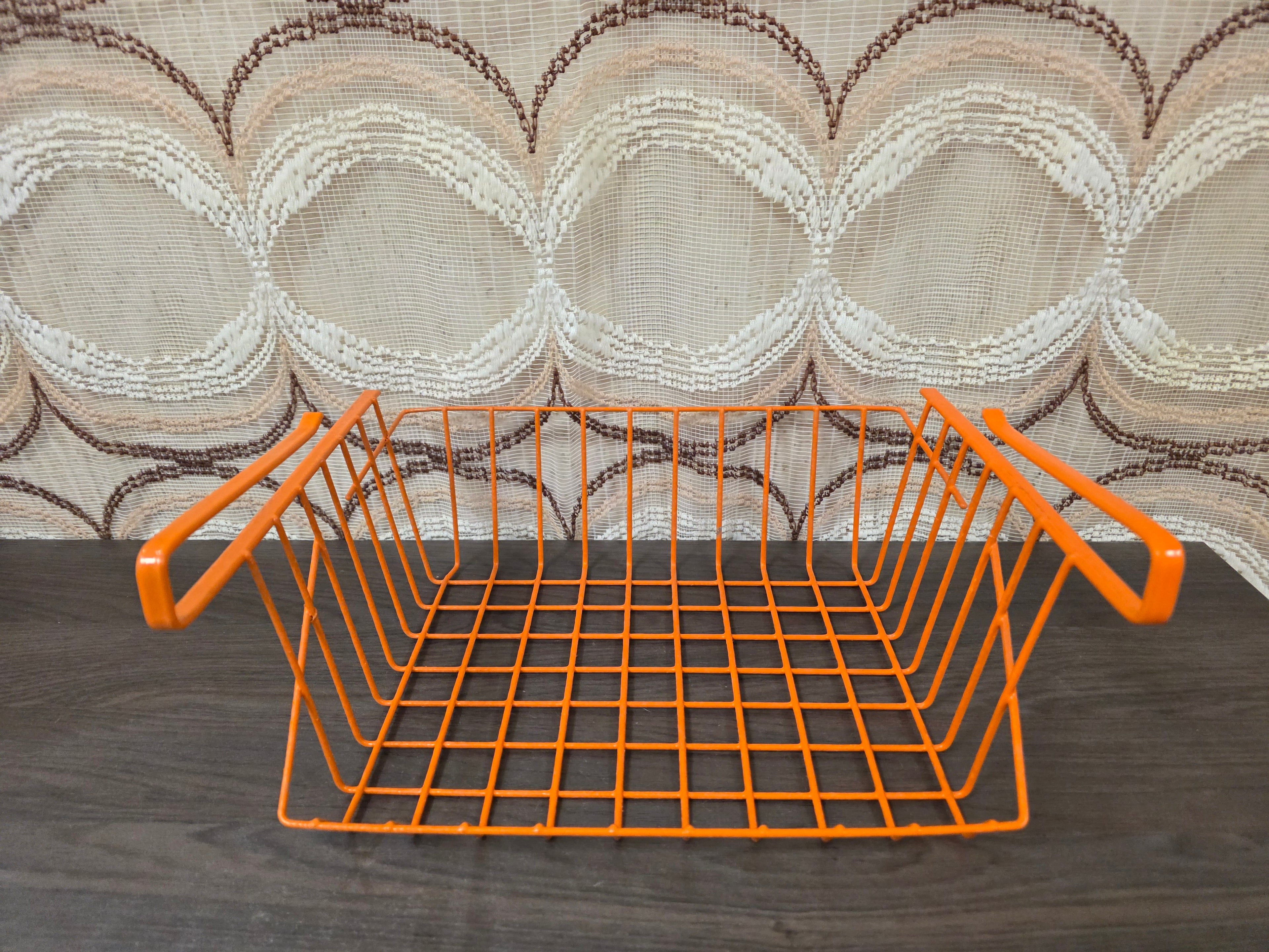 Vintage oranje Tomado draadmand voor montage onder een plank.