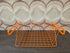 Vintage oranje Tomado draadmand voor montage onder een plank.