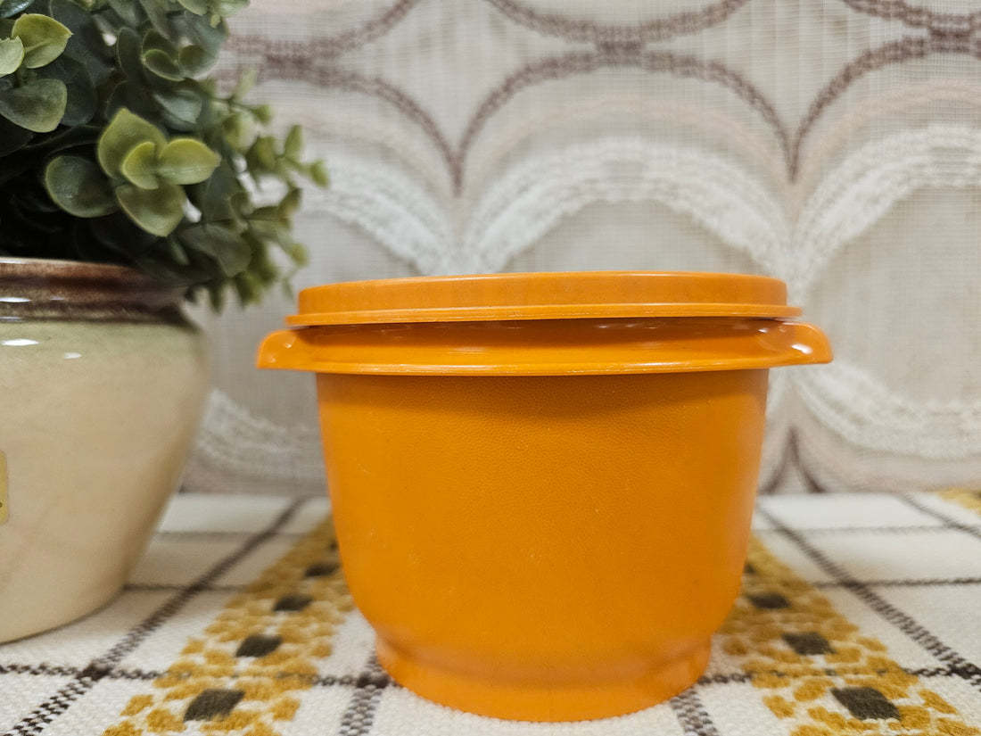Vintage Tupperware trommel in lichtoranje met sterdeksel, diameter 11,5 cm, hoogte 9,5 cm.