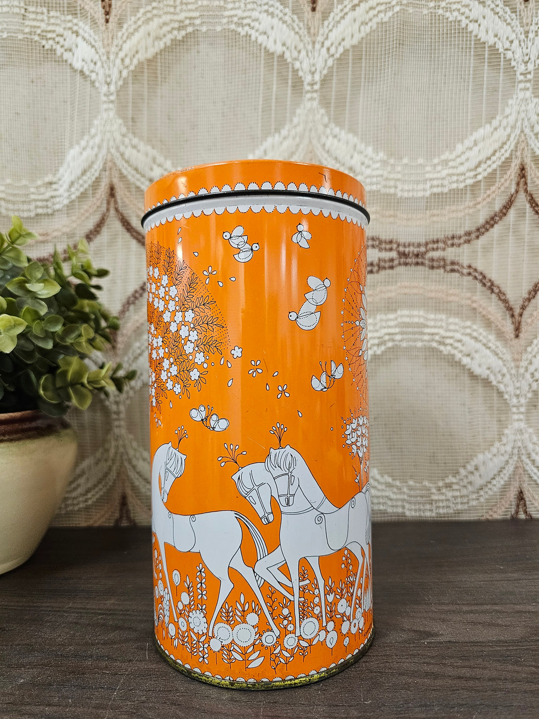 Oranje Verkade beschuitblik met witte afbeeldingen van paarden, bomen, bloemen en kippen, ronde metalen bus.