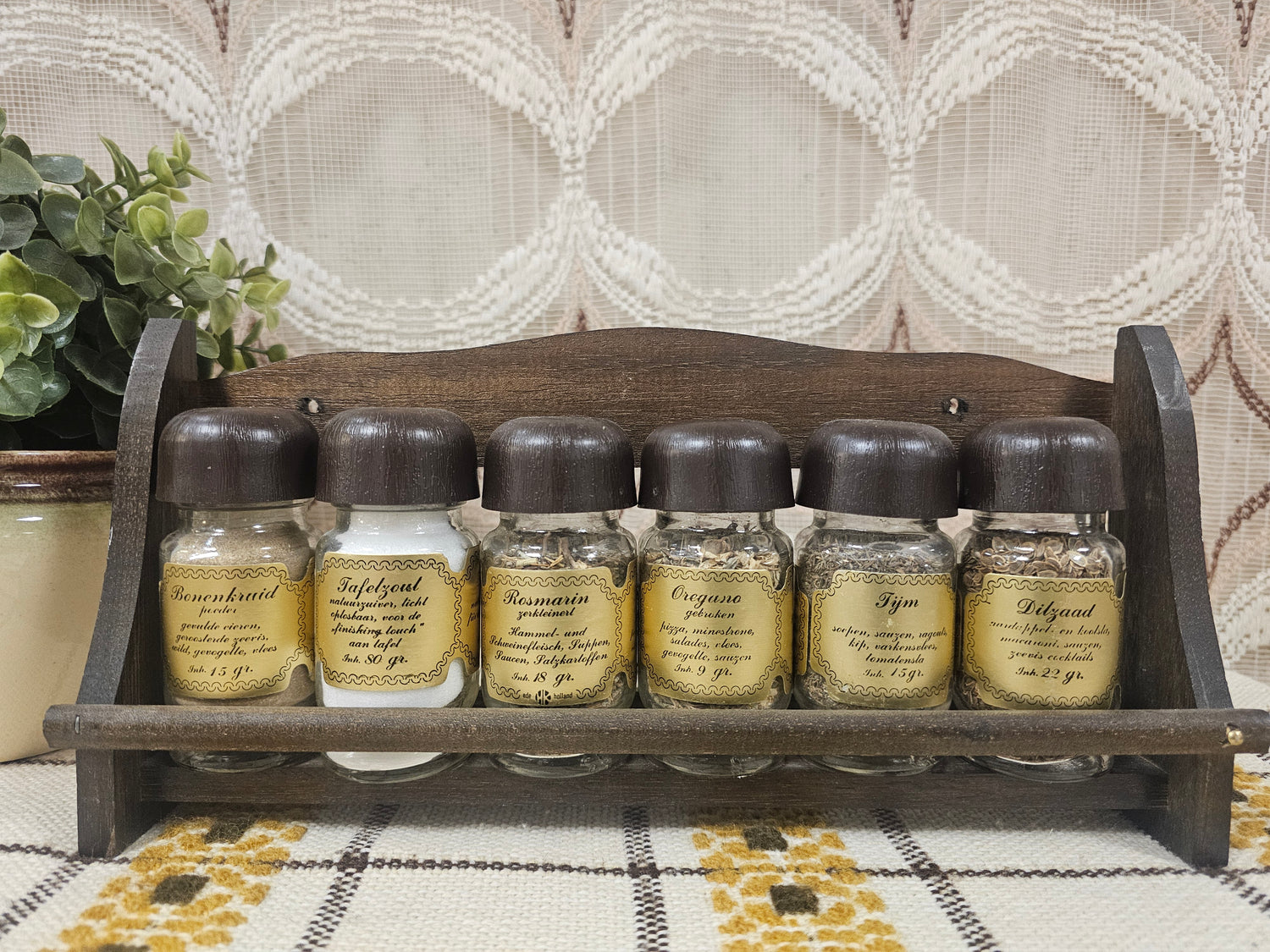 Vintage houten kruidenrek met glazen potjes en goudkleurige labels