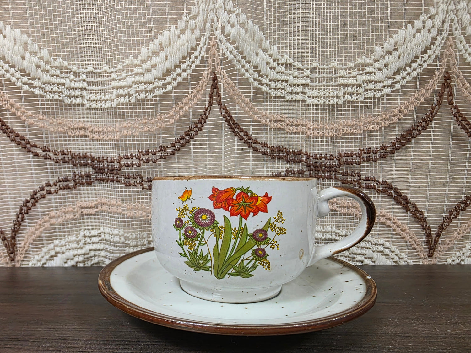 Vintage Wildflower kop en schotel van lichtgekleurd keramiek met subtiele spikkels, bruine rand en een decor van rode en paarse bloemen met kleine veldbloemen.
