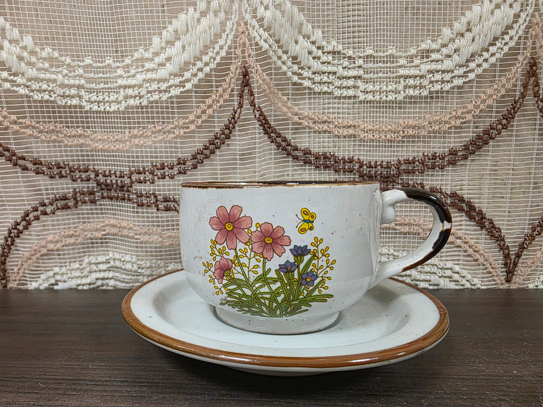 Vintage Wildflower kop en schotel van lichtgekleurd keramiek met subtiele spikkels, bruine rand en een decor van roze bloemen met kleine veldbloeme