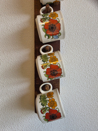 Onderste kopjes met bloemen op het houten mokkenrek