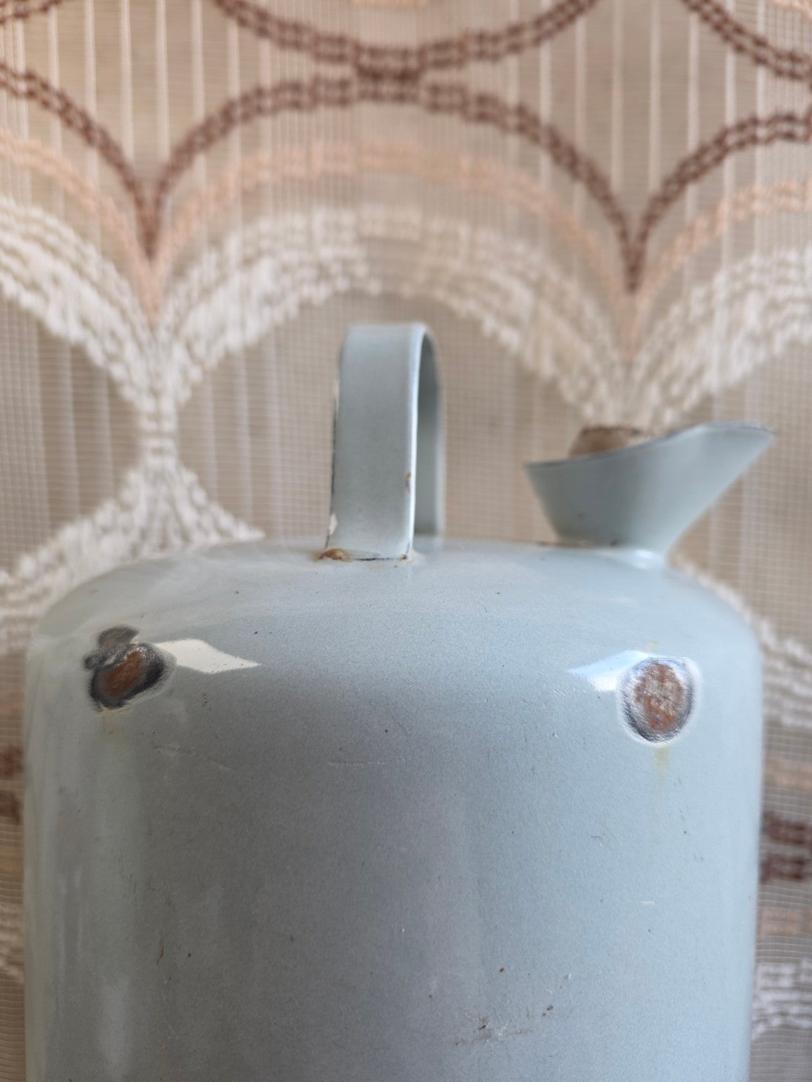 Detail van emaillebeschadigingen en roestplekjes bovenaan de petroleumkan