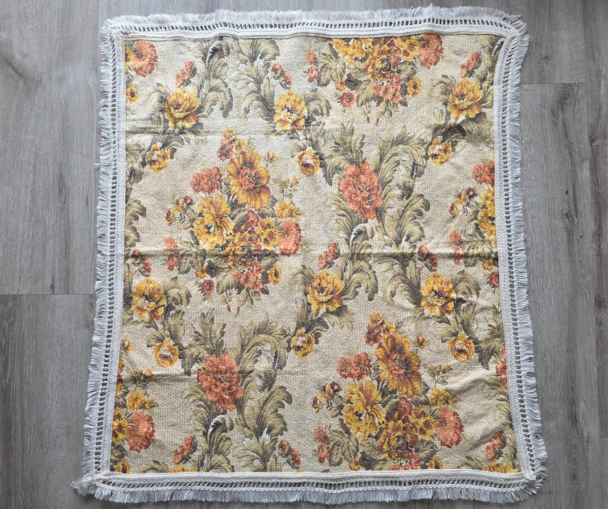 Gebloemd tafelkleed met gele en oranje bloemen en witte franjes