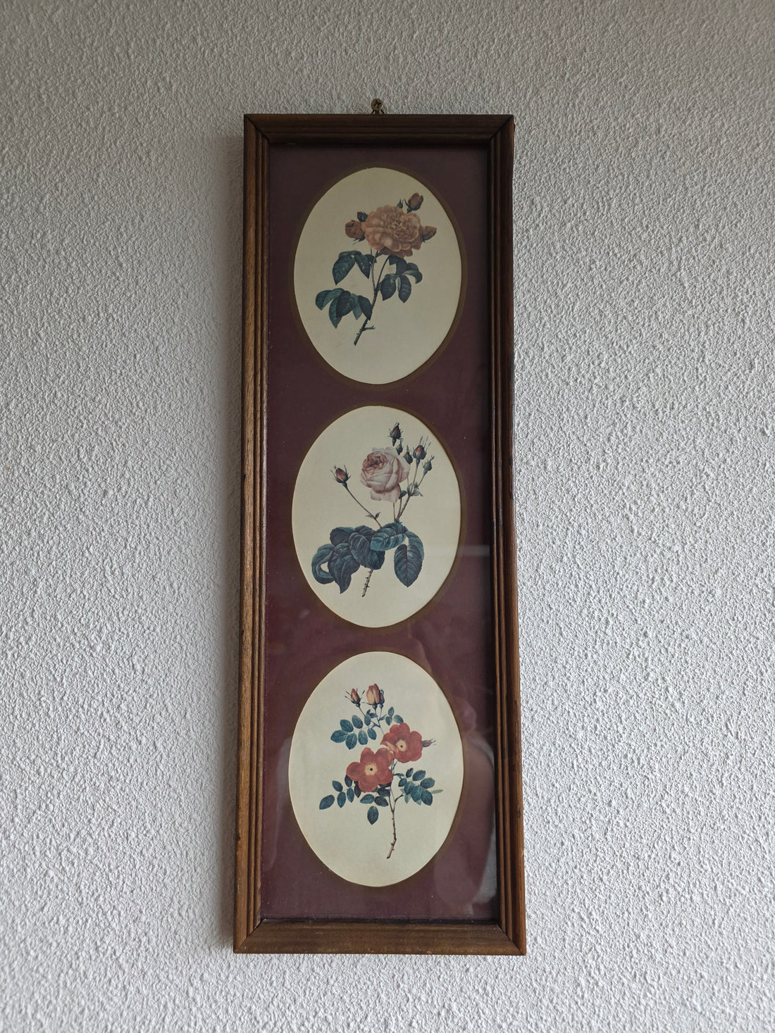 Vintage wanddecoratie met drie botanische rozen in een houten lijst.
