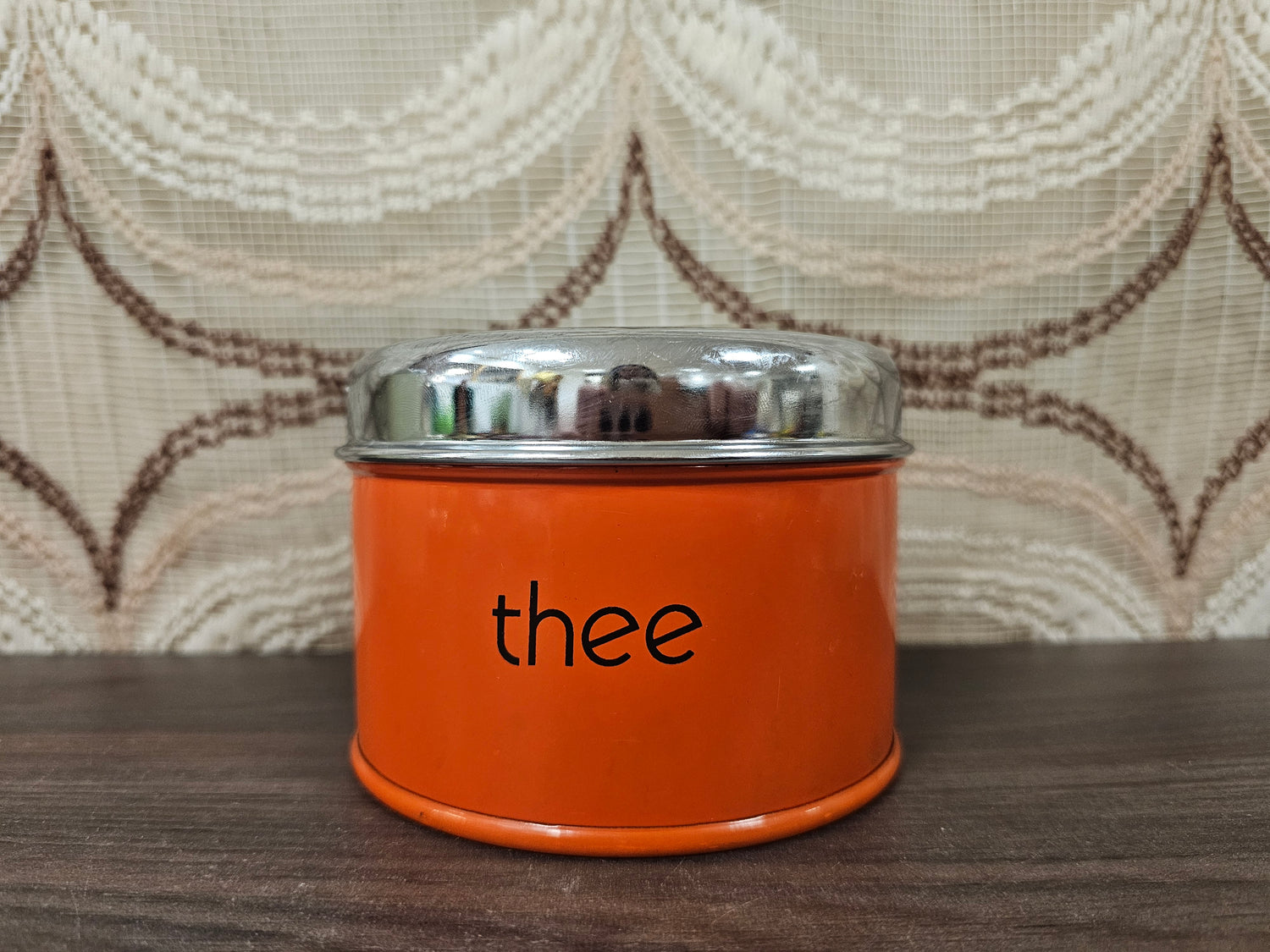Vintage oranje theeblik met zwarte opdruk