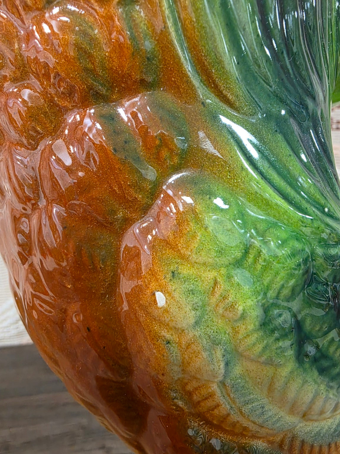 Detail van het groene en bruine glazuur en een klein wit plekje op de zijkant van de haan