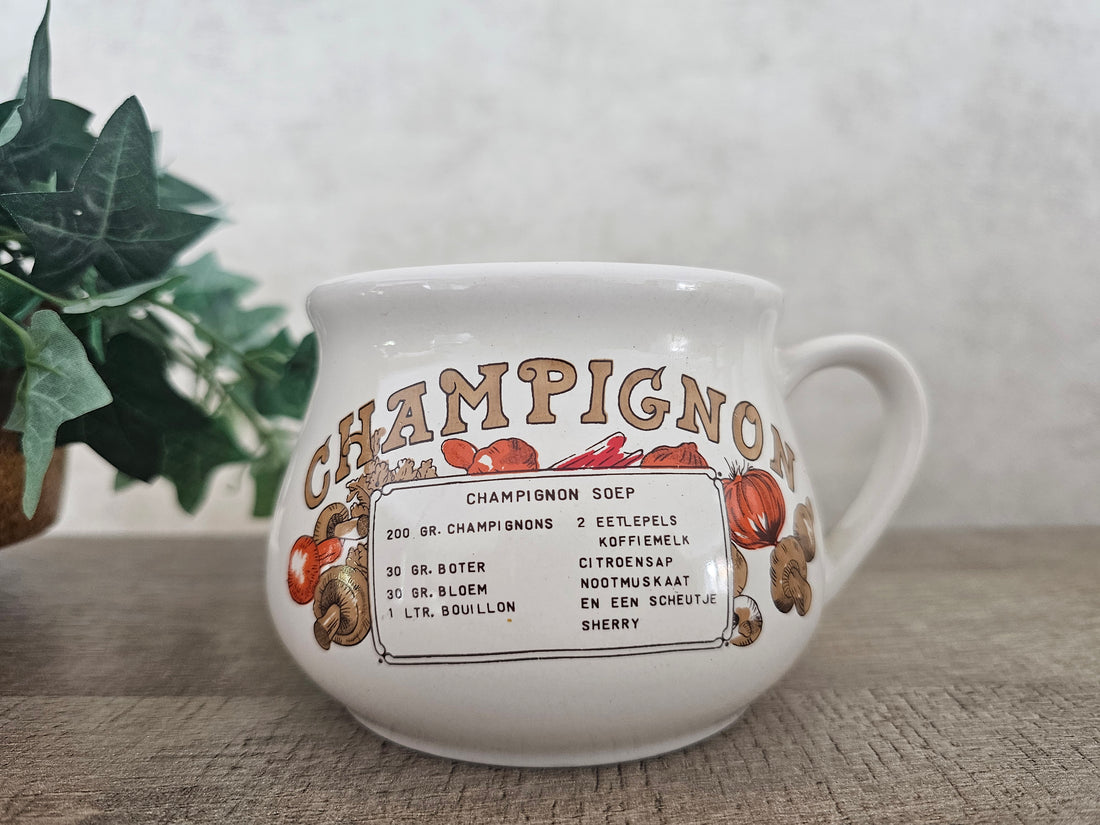 Witte keramische soepkom met champignonsoep recept en de tekst “Champignonsoep” bovenaan.
