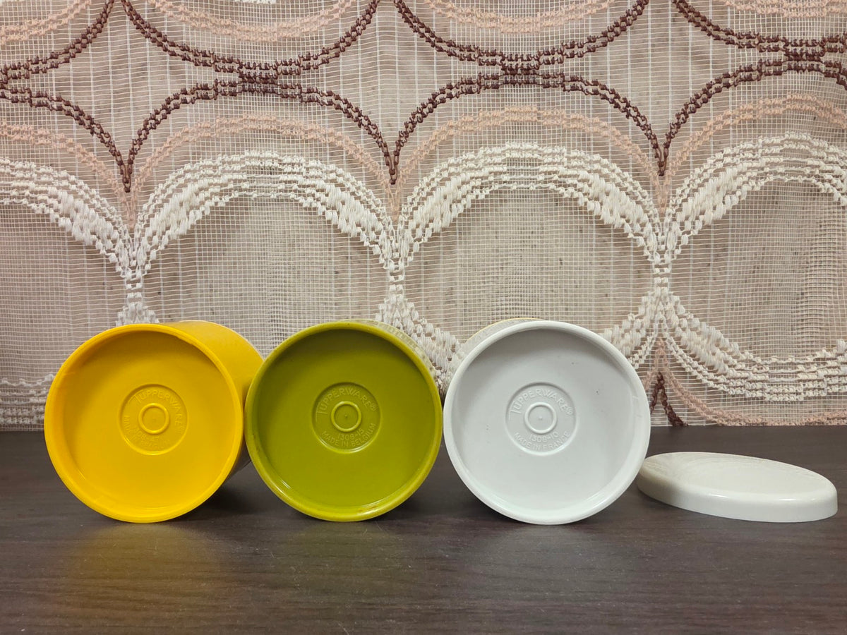Onderkanten van drie Tupperware kruidenstrooiers met merkstempels