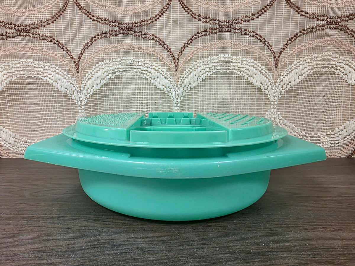 Zijaanzicht van de mintgroene Tupperware rasp op de opvangkom met brede handgrepen