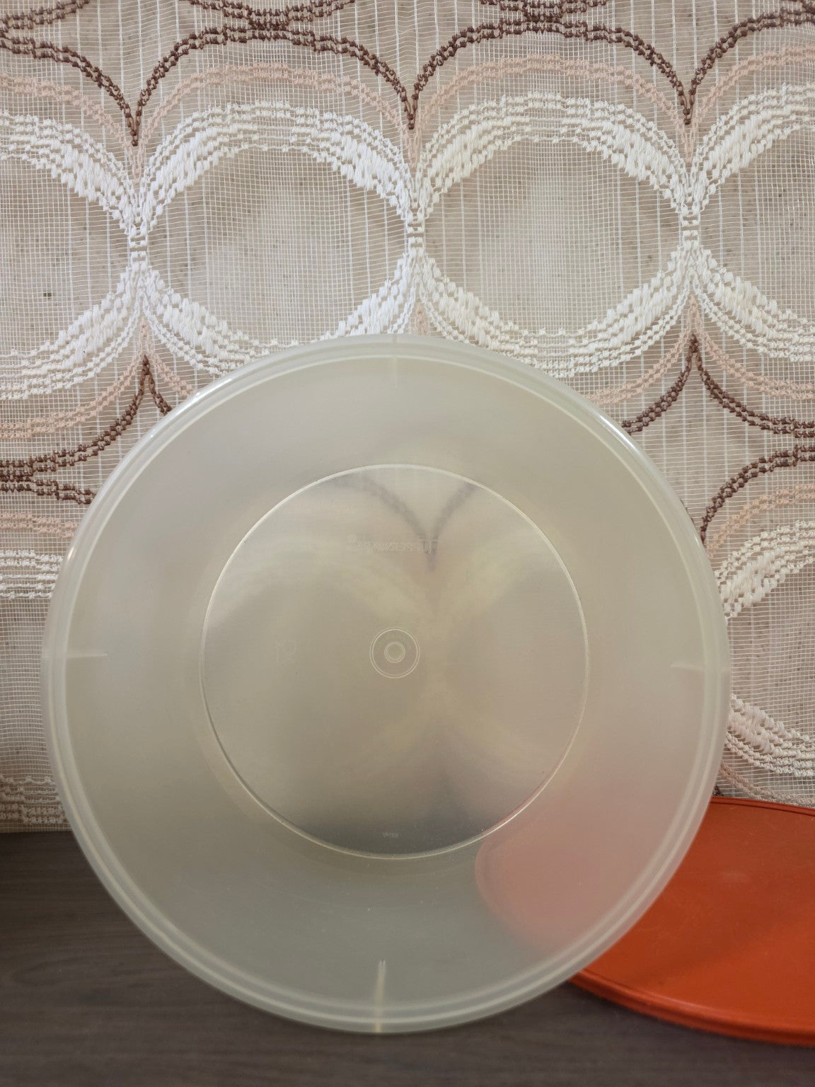 Binnenkant van de ronde Tupperware voorraadbus met het oranje deksel ernaast