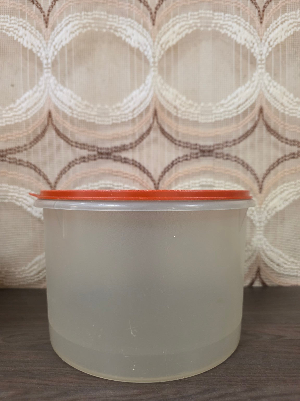 Vooraanzicht van de grote halftransparante Tupperware trommel met oranje deksel