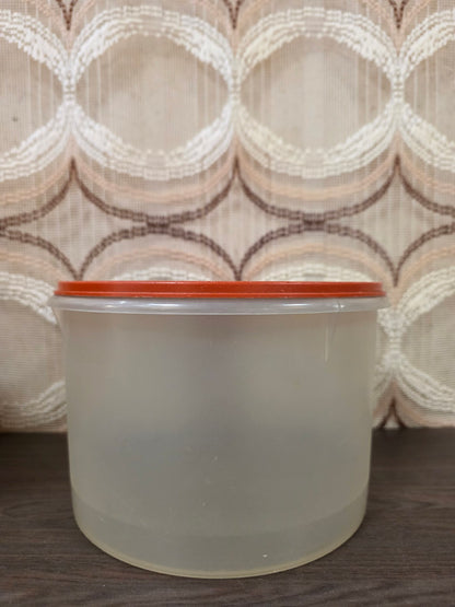 Grote ronde halftransparante Tupperware voorraadbus met oranje deksel, zijaanzicht