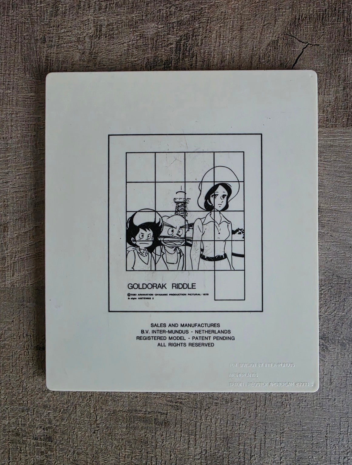 Achterkant Goldorak Riddle schuifpuzzel met voorbeeldafbeelding en vermelding B.V. Inter-Mundus Netherlands